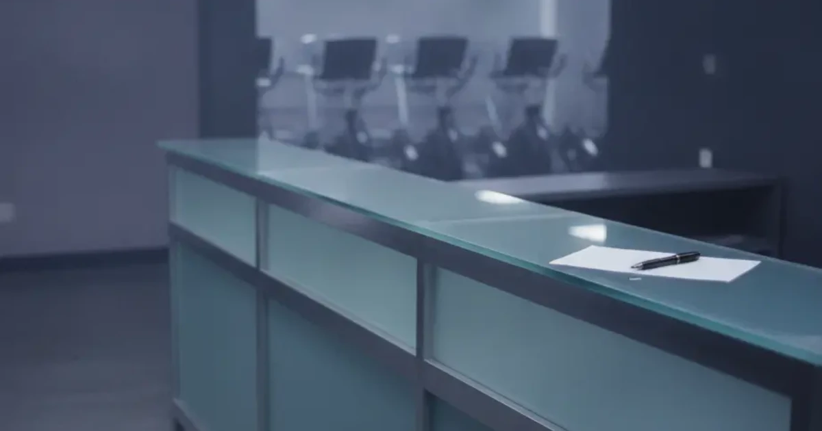 Quiet Planet Fitness reception desk with a member handing a written cancellation letter to staff